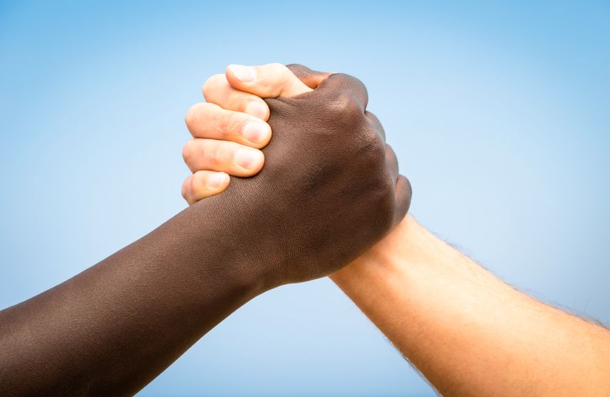 Black and white human hands in a modern handshake to show each o
